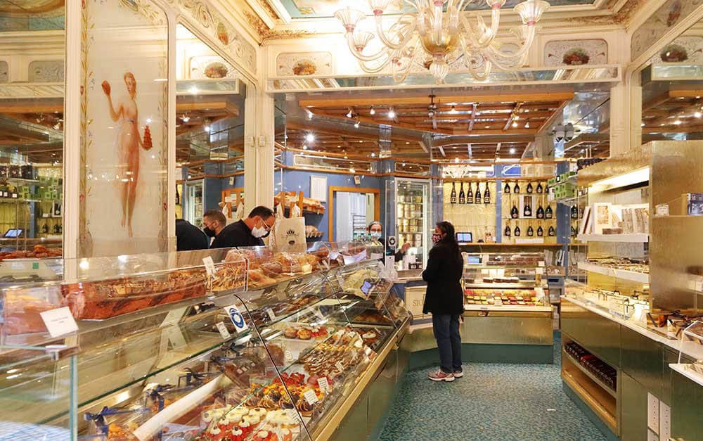 The inside of a Parisian pastry shop with many desserts on a glass counter.
